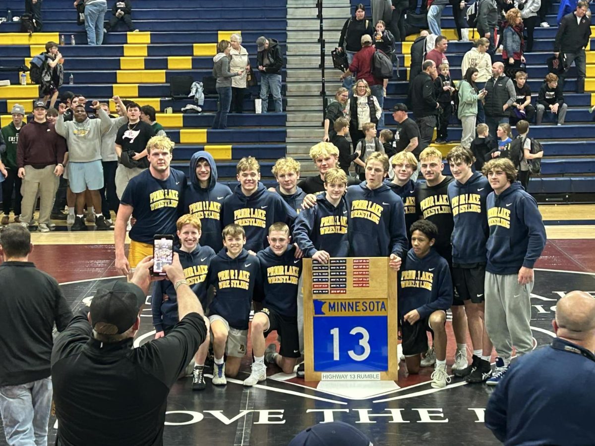 Laker wrestlers posing with the Highway 13 Duals traveling trophy after beating New Prague